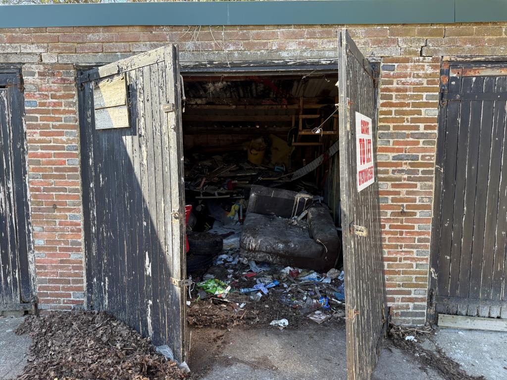 Lot: 33 - FREEHOLD BLOCK OF SEVEN GARAGES WITH POTENTIAL - Garage with barn doors open showing detritus